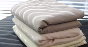 3 different coloured sheets folded on a bed