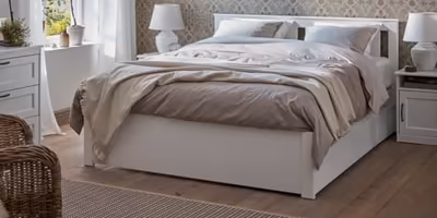 Simple and solid white painted bed frame with messy grey sheets