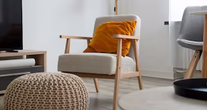 A modern armchair with a grey and an orange cushion