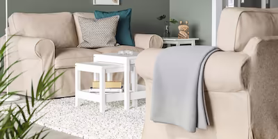 2 small beige 2 seat sofas with thick cushions and a grey blanket