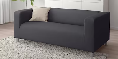 A simple 2 seat sofa in dark grey in the middle of a minimalistic living room