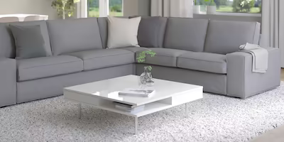 Minimalistic grey 5 seat corner sofa with 2 neutral cushions and a grey blanket